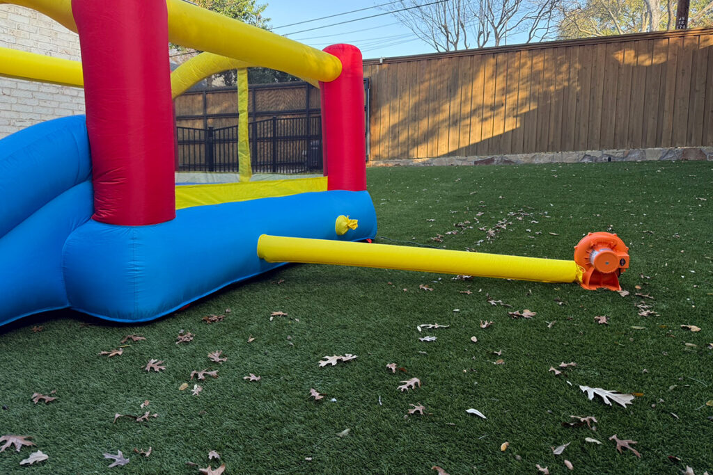 Bounce house setup on green artificial turf in a Dallas backyard on a warm, sunny Christmas morning.
