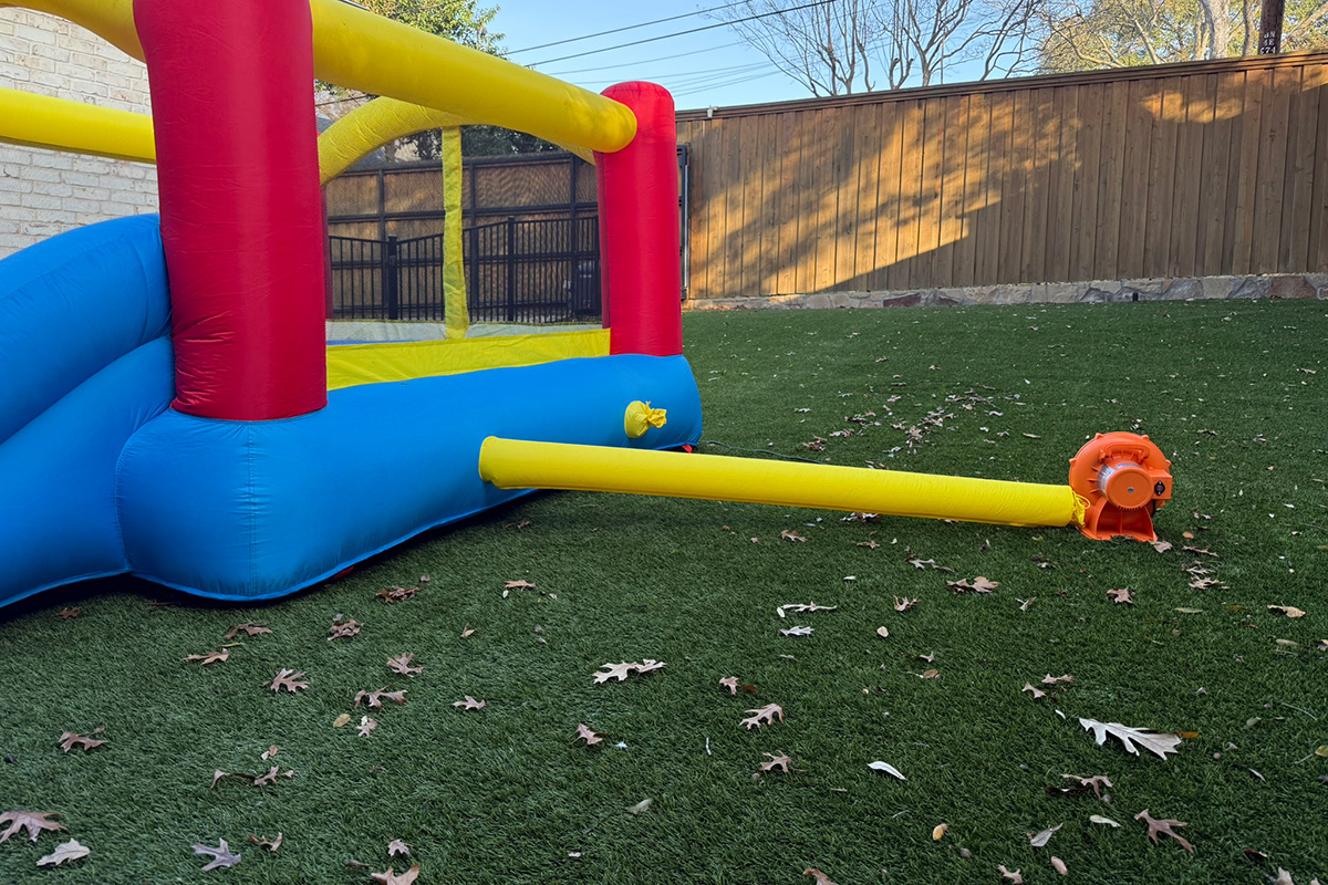 Bounce house setup on green artificial turf in a Dallas backyard on a warm, sunny Christmas morning.