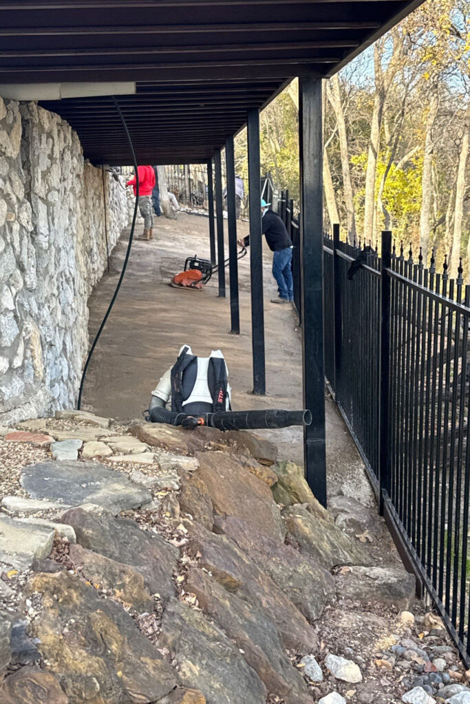 Crew preparing base for winter artificial turf installation on a sloped backyard in DFW