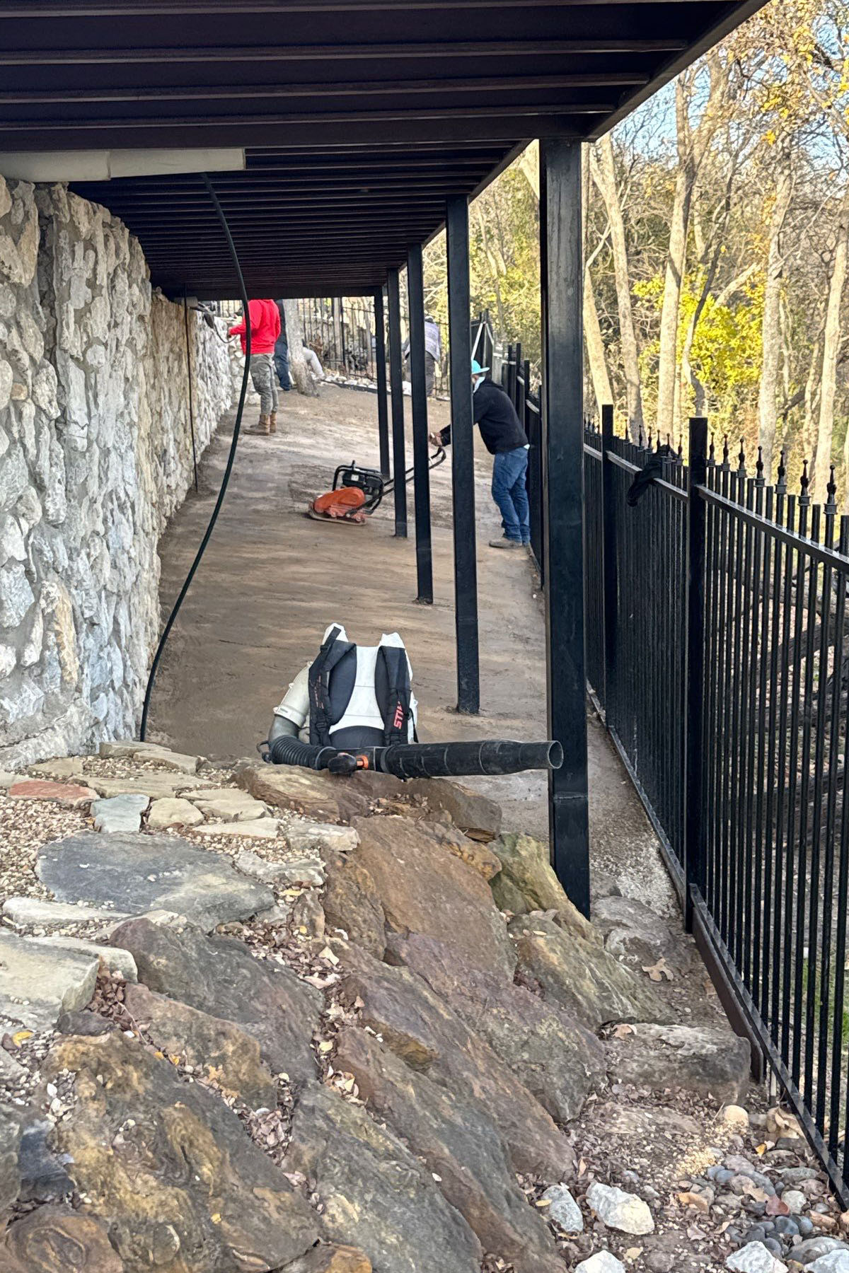 Crew preparing base for winter artificial turf installation on a sloped backyard in DFW